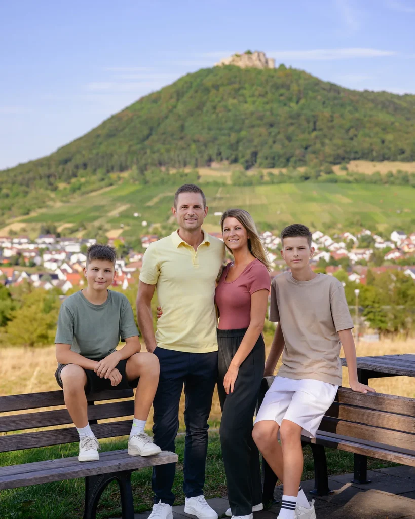 Denis Janzen mit seiner Familie auf einer Bank, im Hintergrund der Hohenneuffen